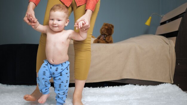 Premium Photo Mom Leads Baby Holding His Hands Forward To Camera First Baby Steps Concept Medium Shot