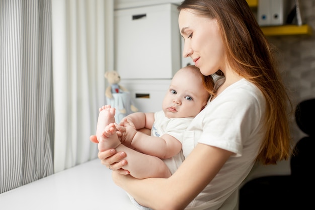 premium-photo-mom-plays-with-the-baby-6-months-on-the-bed-at-home