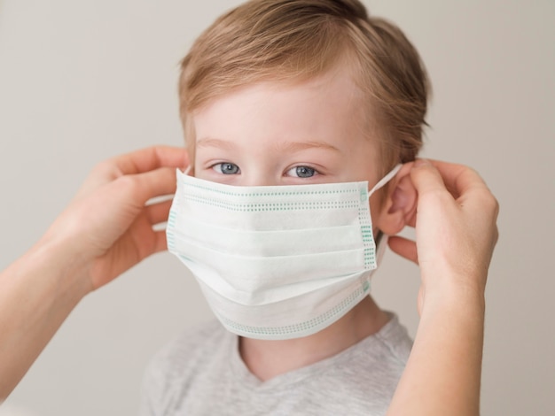 Premium Photo | Mom putting on mask on little boy