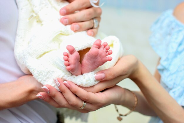 ママの手は 白い暖かい毛布に包まれた生まれたばかりの赤ちゃんの小さな足を保持します プレミアム写真