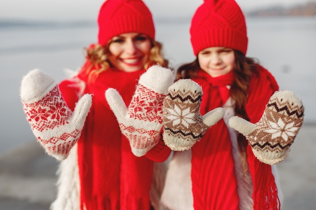 家族のクリスマス休暇にニットの冬の帽子をかぶった母と子 ママと子供のための手作りのウールの帽子とスカーフ 子供のための編み物 ニットアウター 公園の女性と少女 無料の写真