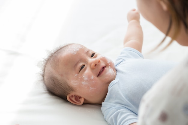 Premium Photo | Mother applying baby powder on the face of the newborn