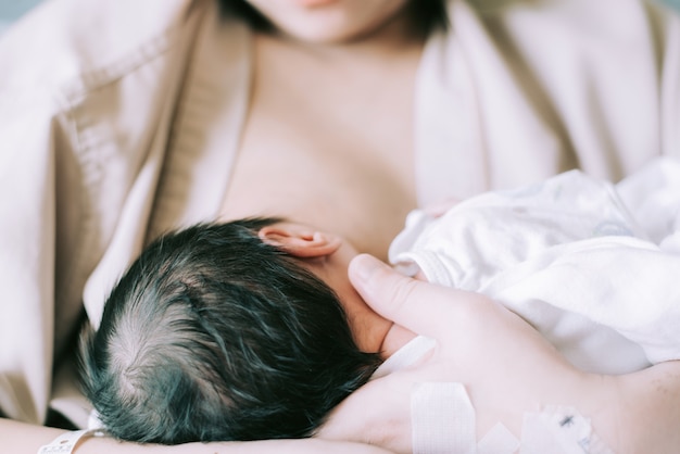 母の母乳と抱きしめる赤ちゃん 若いお母さんは彼女の生まれたばかりの子供を授乳します プレミアム写真