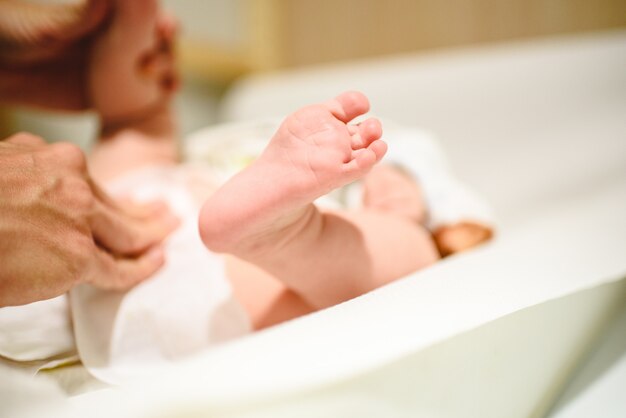 おむつを赤ちゃん 彼女の赤ちゃんの素足に変えるお母さん プレミアム写真