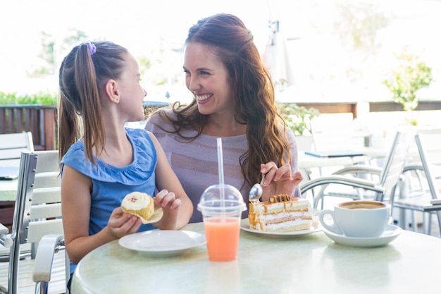 Premium Photo | Mother and daughter enjoying cakes at cafe terrace