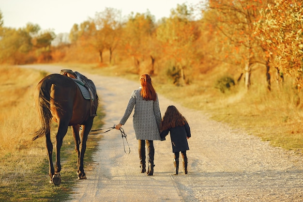 Mother and daughter in a field playing with a horse Free Photo