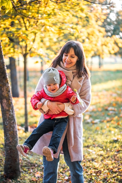 Premium Photo | Mother and daughter having fun in the autumn park among ...