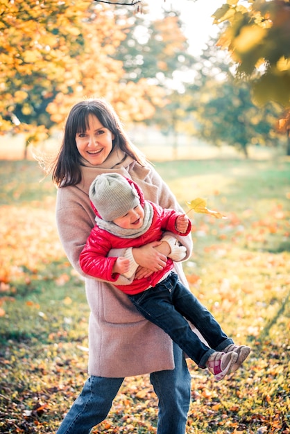 Premium Photo | Mother and daughter having fun in the autumn park among ...