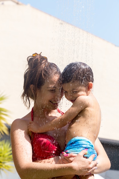 子供たちが水着で笑顔と水をかける母親 プレミアム写真