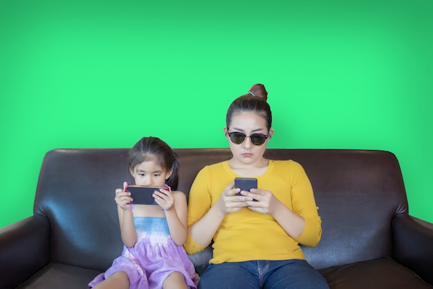 Mother and kid addictation mobile phone play on green screen Premium Photo