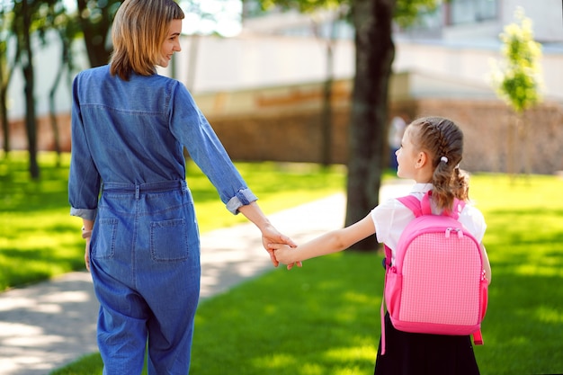 Premium Photo | Mother leads a little child school girl in first grade