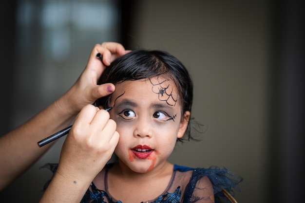 Premium Photo | Mother painting daughters face halloween party