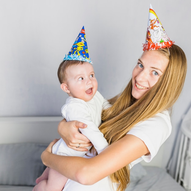 Free Photo Mother playing with her baby wearing hats