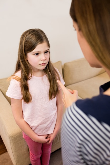 Mother scolding her daughter in living room Photo | Free Download