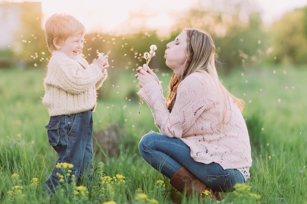 Premium Photo | Mother and son blowing dandelions