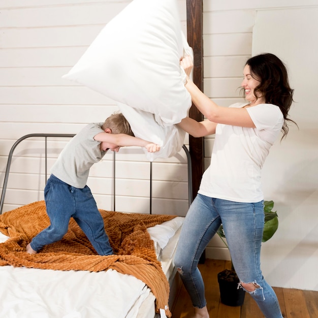 Mother and son having pillow fight | Free Photo