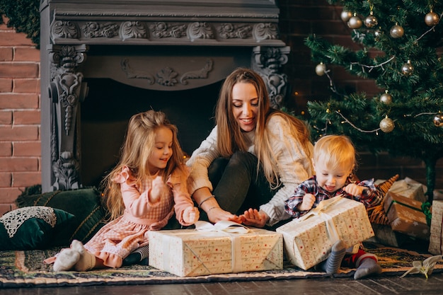 Mother with children by christmas tree Free Photo