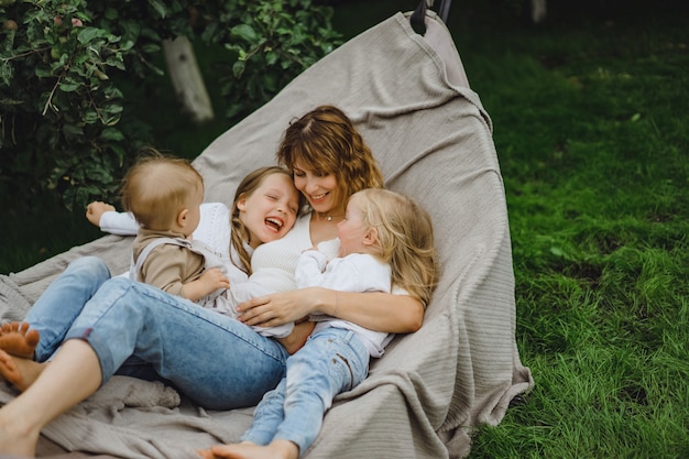 Mother with children having fun in a hammock. mom and kids in a hammock. Free Photo