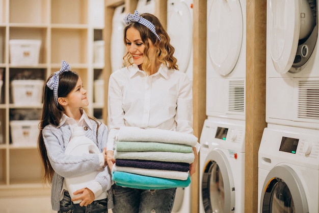 Mother with daughter doing laundry at self serviece laundrette Free Photo