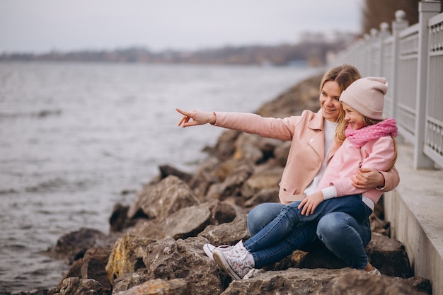 Mother with daughter sitting by the lake Free Photo