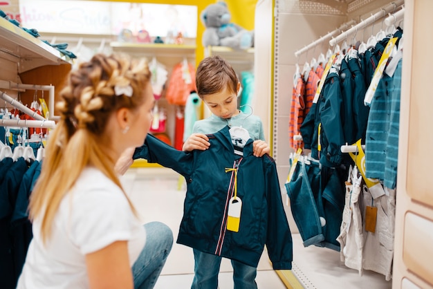 Premium Photo | Mother with her little boy choosing clothes in kids store.