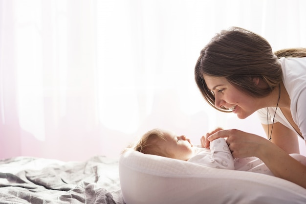 Mother with her newborn son lay on the bed in the rays of sunlight coming out of the window Premium Photo