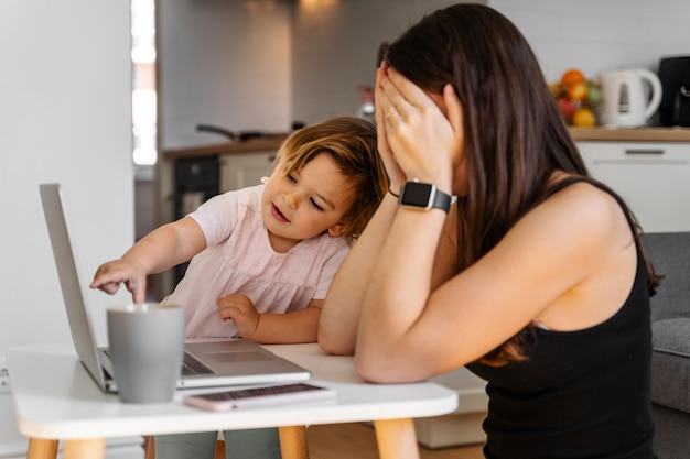 Mother working from home with baby toddler. crying child and stressed woman. stay home Premium Photo