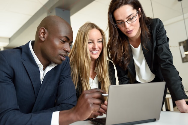 multi-ethnic-group-of-three-businesspeople-meeting-in-a-modern-office-two-caucasian-women-and-a-black-man-wearing-suit-looking-at-a-laptop-computer_1139-966.jpg