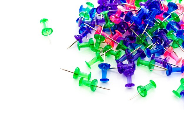 Premium Photo | Multicolored thumbtacks in a pile on a white background.