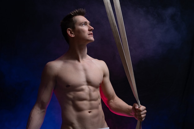 Premium Photo Muscular Male Circus Artist With Aerial Straps On Black And Smoked Background