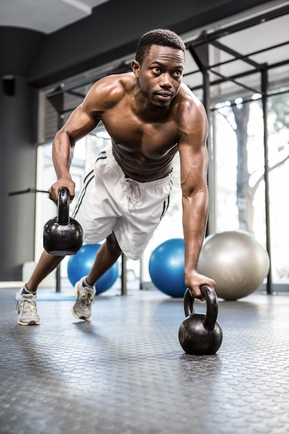 Premium Photo | Muscular man doing push up with kettlebells at the ...