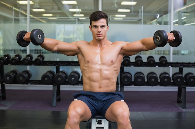 Premium Photo | Muscular man exercising with dumbbells in gym