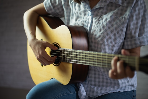 アコースティックギターを演奏するミュージシャンの女の子 プレミアム写真
