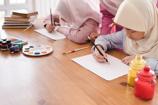 Muslim woman teaching her children painting and drawing at home. Premium Photo