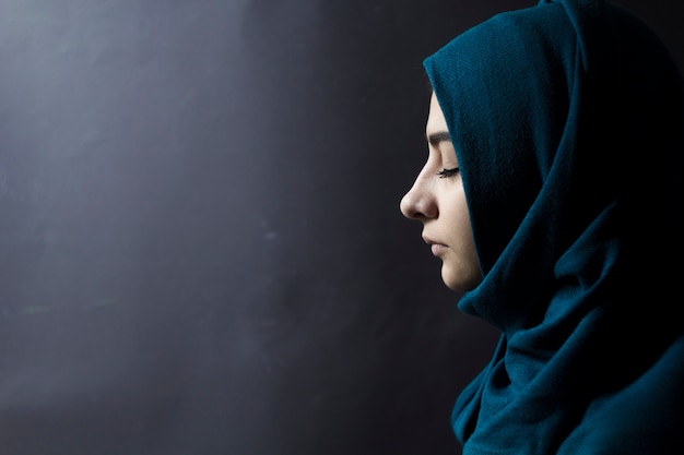 A Muslim Woman With Closed Eyes On A Black Background