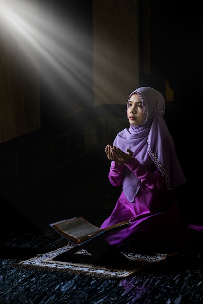Muslim women wearing purple shirts doing prayer according to the principles of islam. Premium Photo