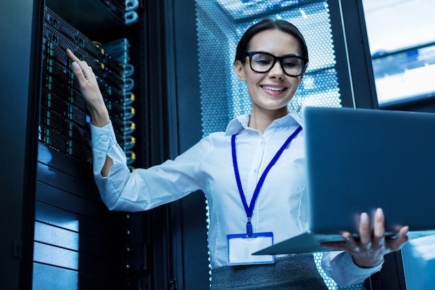 My best day. content attractive woman working in a server cabinet and holding her laptop Premium Photo