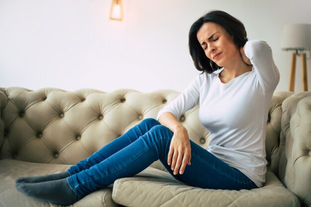 Premium Photo | Neck strain symptoms. young lady is sitting at home on ...