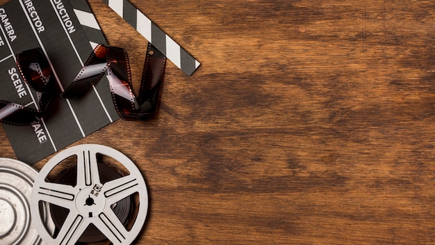 Negatives stripes with clapperboard and film reels on wooden desk Free Photo