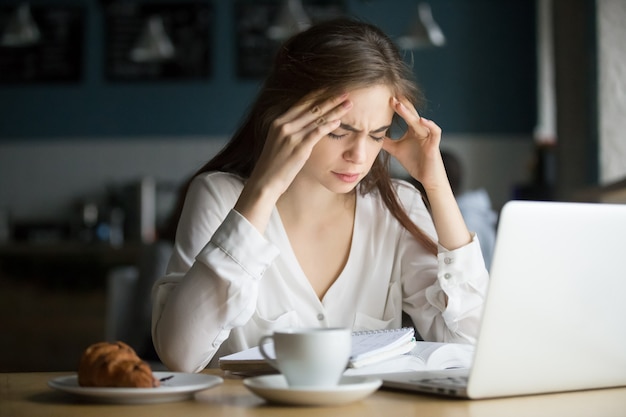 Nervous stressed female student feeling headache studying in cafe Free Photo