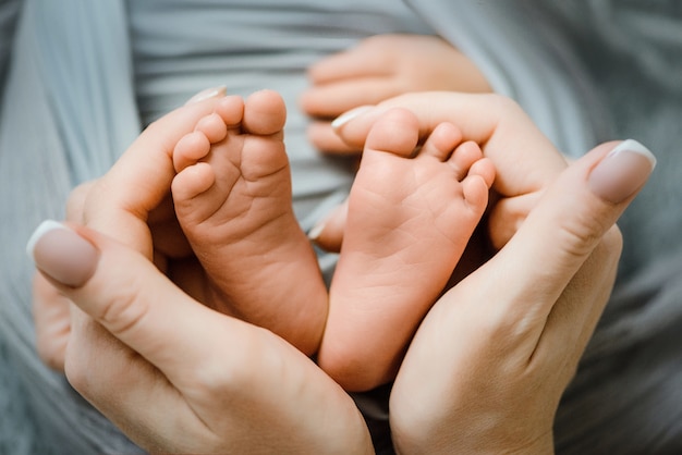 女性の手で生まれたばかりの赤ちゃんの足 かわいいハートのような形 プレミアム写真