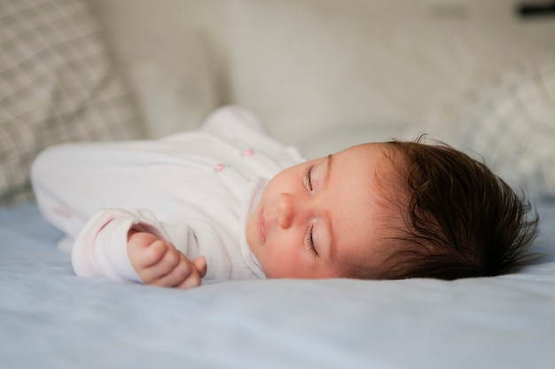 Newborn baby girl sleeping on blue sheets at home Free Photo