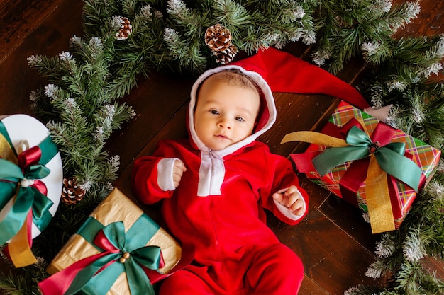 サンタクロースの衣装で生まれたばかりの赤ちゃんは クリスマスツリーの花輪の真ん中にあります プレミアム写真