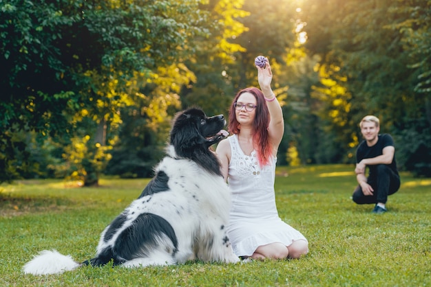 ニューファンドランド犬は公園で男女と遊ぶ プレミアム写真