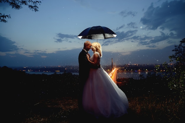 Premium Photo Newlyweds Kissing Under An Umbrella At Dusk