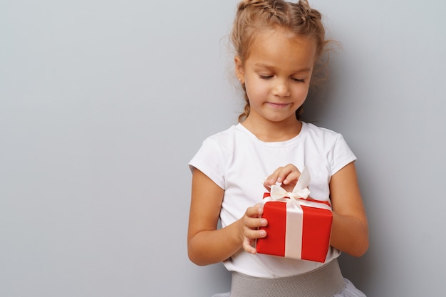 Premium Photo | Nice little girl holding a red gift box in her hands