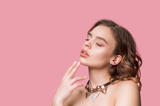 Nice young smiling woman with long wavy silky hair, natural make up with hand near chin isolated on pink wall. Free Photo