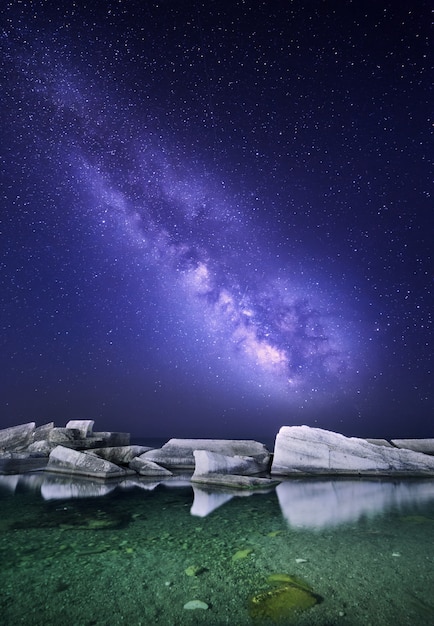 石と海でカラフルな天の川の夜の風景 星空 スペースの背景 プレミアム写真