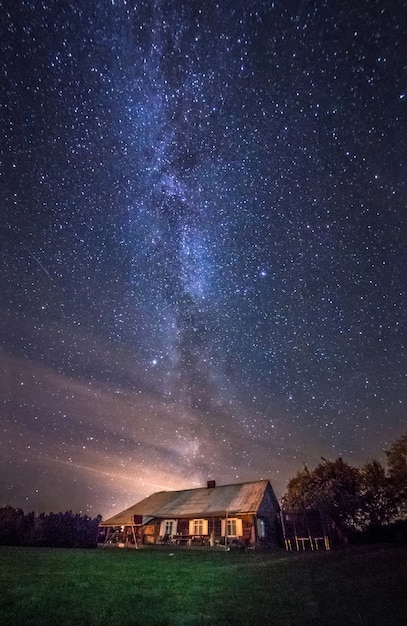 天の川の星が街の外にある田舎の家の夜の風景 プレミアム写真