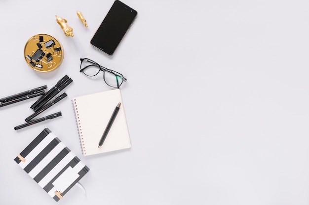 Notebook; felt-tip pen; eyeglasses; stationery and cellphone on white background Free Photo